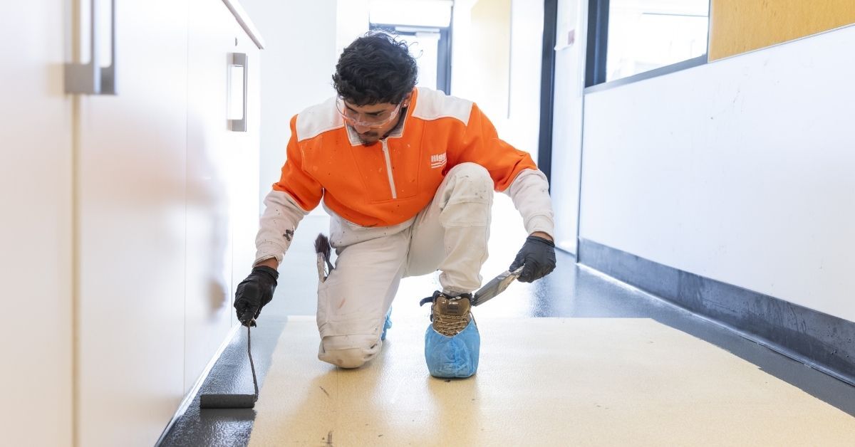 specialist applying a precise protective coating during a commercial floor rejuvenation project.